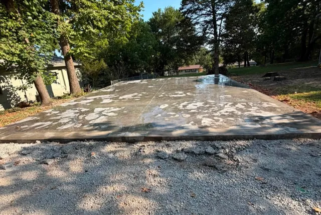 Poured slab, Alpena AR A finished concrete slab on a wooded lot with a gravel apron along its front edge
