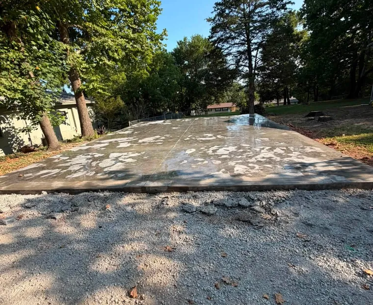 A finished concrete slab poured on a prepared base, with a gravel apron along its front edge