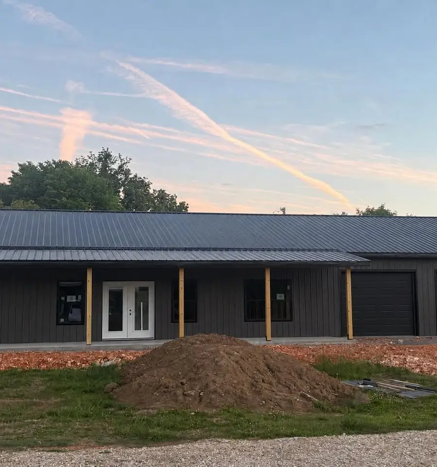 Custom Home Building A completed post-frame home built by Sundown, dark metal walls and roof with a covered porch and twin garage bays