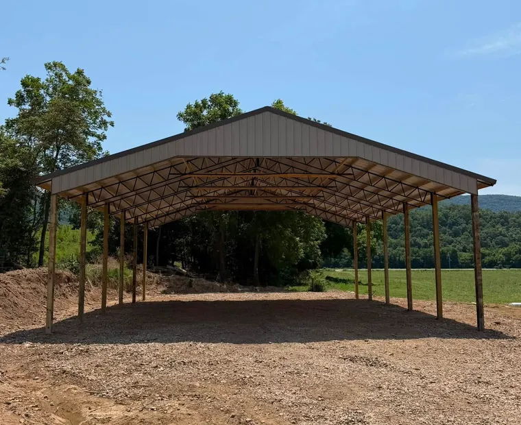 Car Ports An open-sided covered structure on timber posts with a metal gable roof, standing on gravel