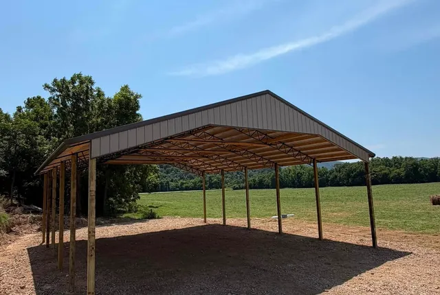 Post-frame shelter beside pasture, Jasper AR The same shelter from the side, its open bays looking through to green pasture and hills