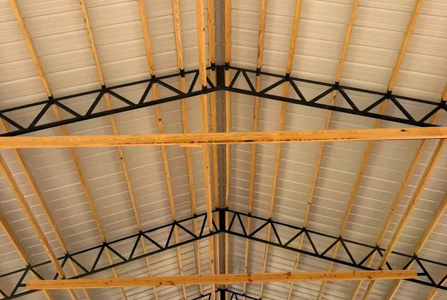 Steel truss roof structure, Jasper AR The underside of the roof, showing black steel trusses, timber purlins and cream metal panel