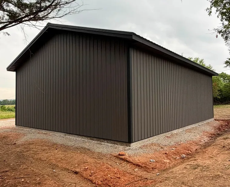 Siding A building finished in charcoal metal siding, showing the panel ribs, corner trim and base detail above a concrete stem wall