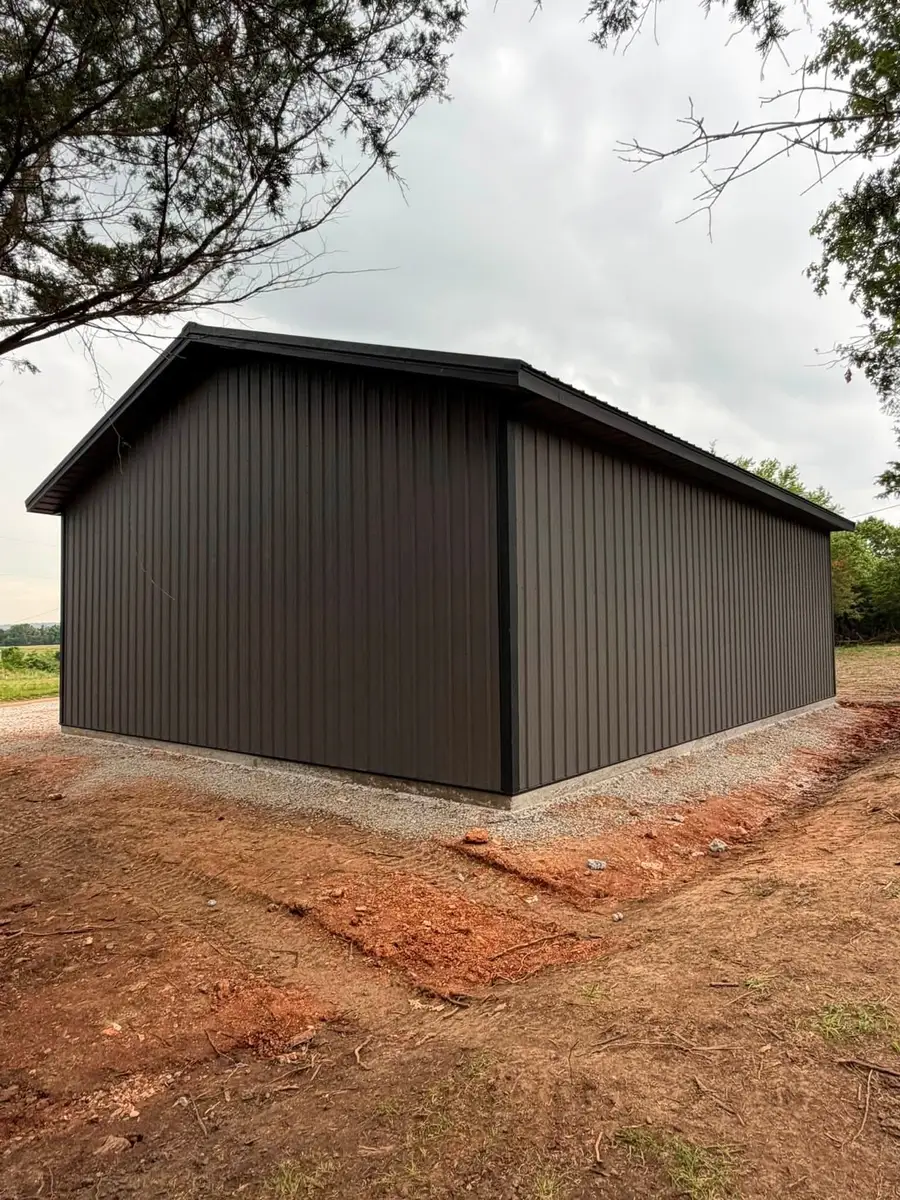 Siding A building finished in charcoal metal siding, showing the panel ribs, corner trim and base detail above a concrete stem wall