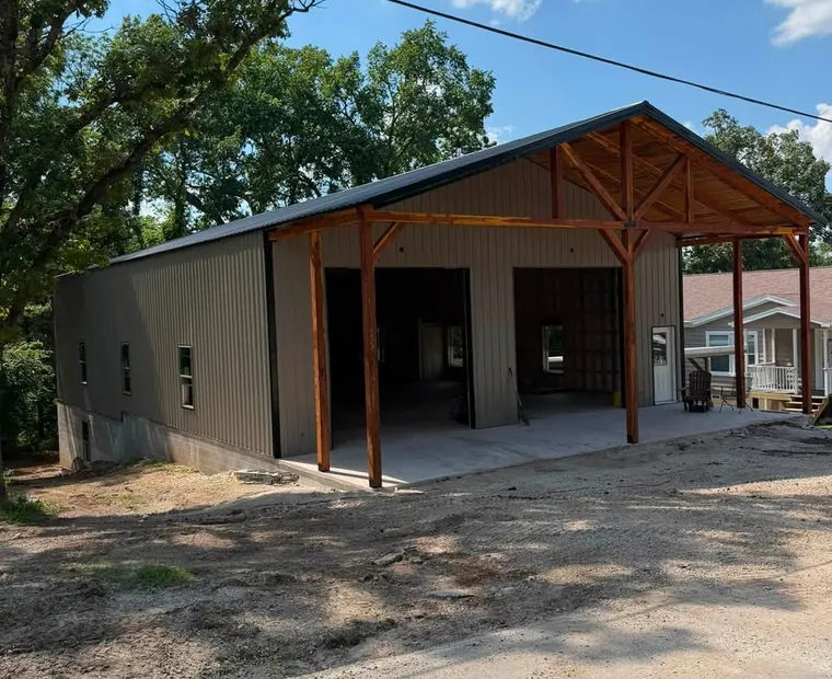 Shops & Garages A finished metal shop with a dark roof, stained timber porch posts and two open bays on a concrete apron