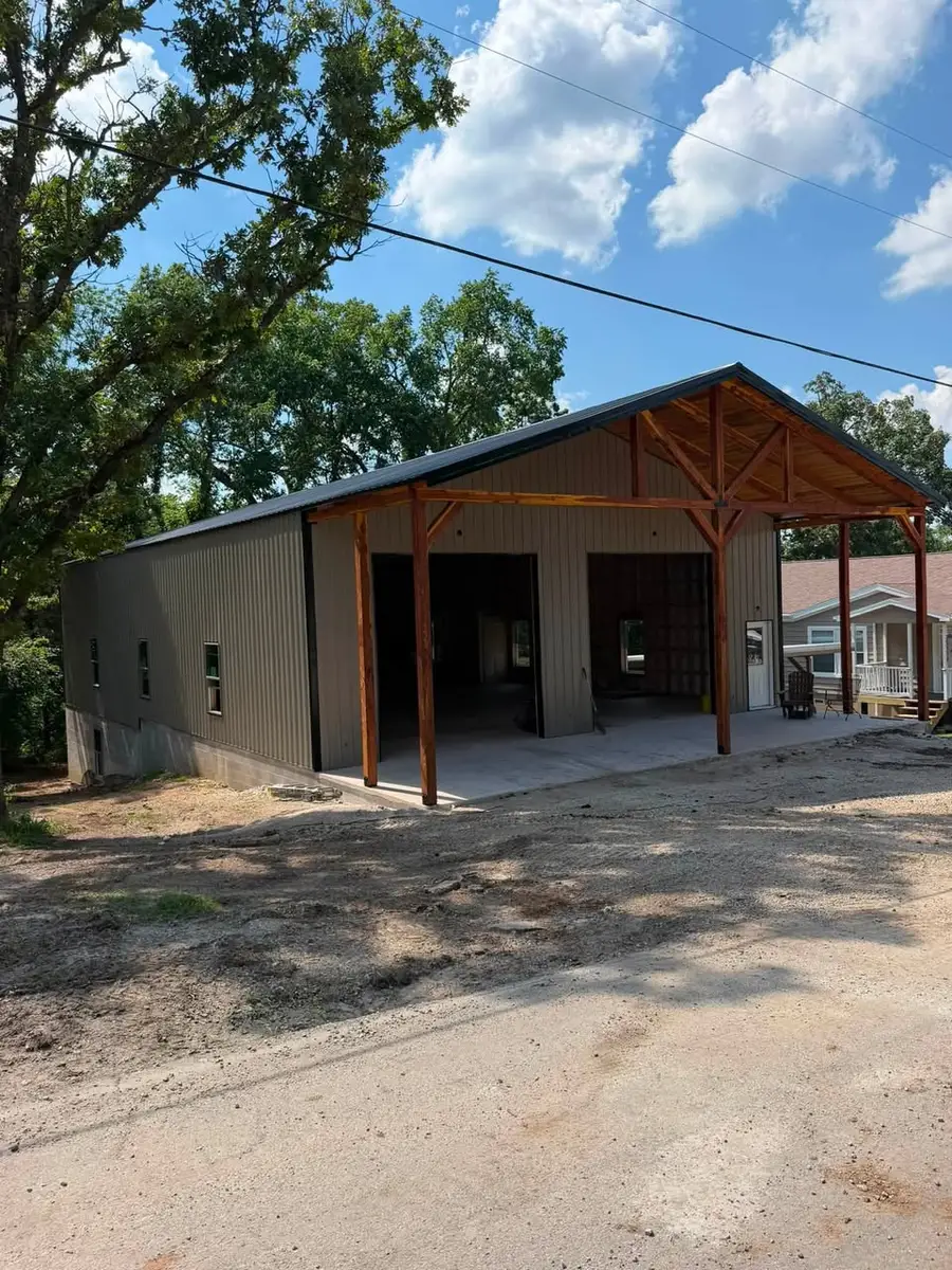 Shops & Garages A finished metal shop with a dark roof, stained timber porch posts and two open bays on a concrete apron